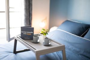 a table with two cups and a box on a bed at Charming and Natural T2 neuf - Hyper-centre Meaux - Disneyland Paris in Meaux
