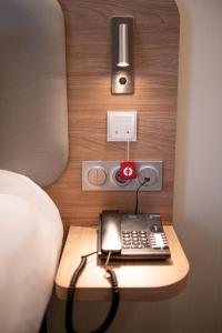 a phone on a table next to a bed at Holiday Inn Express - Arcachon - La Teste, an IHG Hotel in La Teste-de-Buch