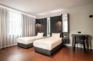 a bedroom with two beds and a desk and a mirror at Point A Hotel London Paddington in London +30 photos