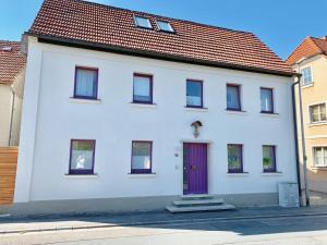a white house with a purple door on a street at Ferienhaus Maria in Walsdorf