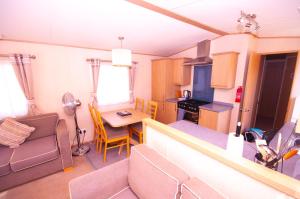 a kitchen and living room with a table and chairs at Caravan by Camber Sands 2 in Camber