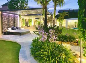 un patio trasero con una cama y un jardín con flores púrpuras en Villa Turrion, en Marbella