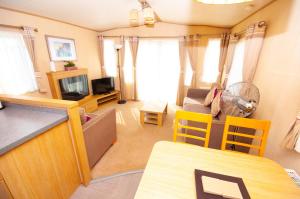 Caravan by Camber Sands 2 في Camber: غرفة معيشة مع مطبخ وغرفة معيشة مع تلفزيون