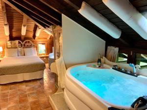 1 dormitorio con bañera grande y cama en La Casa Del Puente, en Regules