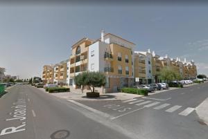 una calle vacía con edificios y coches estacionados en un estacionamiento en Apartamento Felicidade, en Almancil
