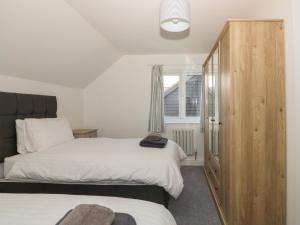 a bedroom with two beds and a wooden cabinet at The Glass House in Hunstanton