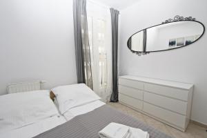 biała sypialnia z łóżkiem i lustrem w obiekcie Promenada by Baltic Home w Świnoujściu +37 zdjęć