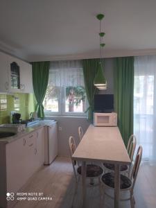 uma cozinha com uma mesa com cadeiras e um micro-ondas em Brill Apartman em Harkány