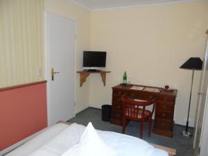 a bedroom with a bed and a desk with a television at Landhaus Schulze-Hamann - Hotel garni - in Blunk