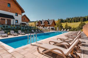 a row of lounge chairs next to a swimming pool at Czeremcha - Ostoja Bukowinki in Jaworki