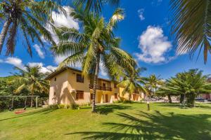 a house with palm trees in front of it at America Praia Flat - Portal Hotéis in Porto Seguro