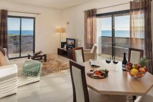 a living room with a table with a bowl of fruit and wine glasses at Belmar Spa & Beach Resort in Lagos