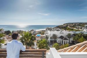 a man standing on a balcony looking at the ocean at Belmar Spa & Beach Resort in Lagos