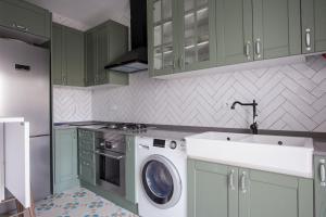 a kitchen with green cabinets and a washing machine at El ático de los mosaicos in Cádiz +15 photos