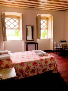 a bedroom with a bed with a floweredspread and two windows at Pousada Colonial Penedo - Alagoas in Penedo