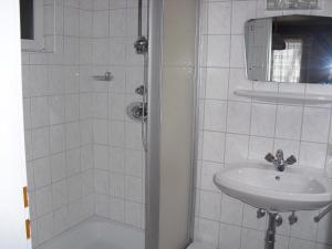 ein weißes Bad mit einem Waschbecken und einer Dusche in der Unterkunft Gasthof Zum heiligen Nikolaus in Haibach ob der Donau