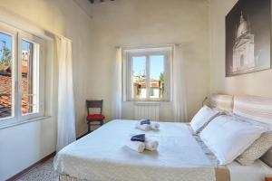 a bedroom with a bed with towels and two windows at Terrazza San Martino in Lucca