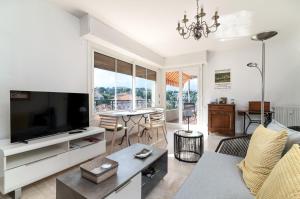 a living room with a television and a table with chairs at COPACABANA appartement 2 chambres in Cannes