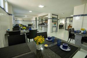 - une salle à manger avec des tables, des chaises et des fleurs dans l'établissement Hotel Pousada do Farol, à Aracaju