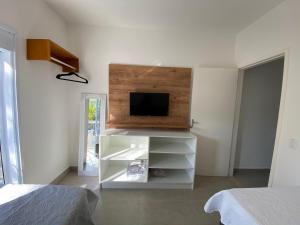 a white entertainment center with a tv on a wall at Apto Novo Duplex em Juqhey in Juquei