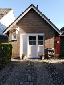a garage with a white door and a brick house at Tante Cher à la Mer - Zeeland in Biggekerke