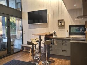 a kitchen with a bar with stools and a television on the wall at Les Kabanes de Kerforn in Crach
