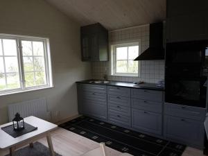 a kitchen with black cabinets and a table and windows at Sjötorpet - unikt boende vid havet på norra Öland! in Löttorp