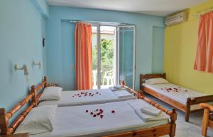 2 Betten in einem Zimmer mit roten Blütenblättern drauf in der Unterkunft Belvedere Zakynthos Studios in Vasilikos