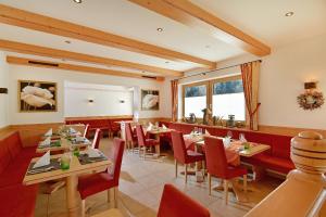 a restaurant with wooden tables and red chairs at Pension Aloisia in Scheffau am Wilden Kaiser