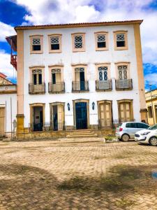 duży biały budynek z samochodami zaparkowanymi przed nim w obiekcie Pousada Colonial Penedo - Alagoas w mieście Penedo