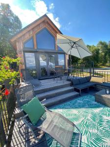 une maison avec une terrasse dotée de chaises et d'un parasol dans l'établissement Domek w Widokowej Osadzie, à Międzylesie