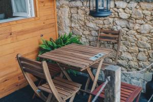 a wooden table and two chairs next to a stone wall at Siglas & Runas II in Póvoa de Varzim