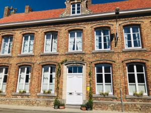 - un bâtiment en briques avec des portes et des fenêtres blanches dans l'établissement B&B Le Cloître St Joseph, à Messines