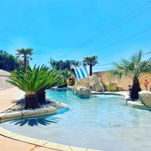 einen Pool mit Palmen und einer Wasserrutsche in der Unterkunft Camping La Montagne in Sorgues