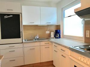 Una cocina con gabinetes blancos y un fregadero y una ventana. en Ferienwohnung Lechner Traudi Kreuzschied 141, en Neukirchen am Großvenediger