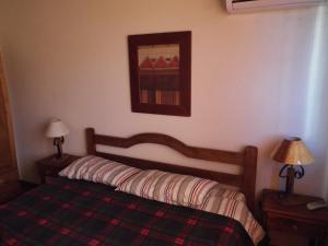 a bedroom with a bed with a plaid blanket and two lamps at El Remanso De Almiron in Termas de Almiron