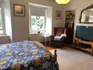 a bedroom with a bed and a tv and a chair at 3 Bedroom 2 Bathrooms Apartment in Central Penzance in Penzance