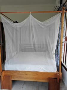 a canopy bed with a white sheet on it at Upper Inchaban beachfront apartment in Inchaban