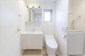 La salle de bains blanche est pourvue de toilettes et d'un lavabo. dans l'établissement Salon Shibuya - Vacation STAY 78187, à Tokyo