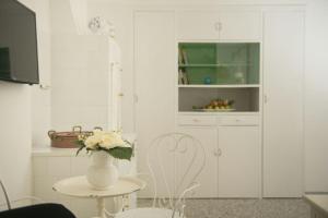 uma cozinha branca com um vaso de flores sobre uma mesa em Dimora Cappuccini Guest House em Cisternino