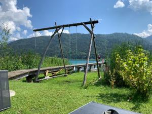eine Schaukel auf einem Dock mit einem See in der Unterkunft Haus Waldblick in Weissensee