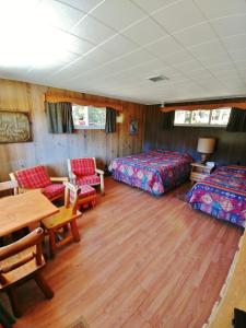 a room with two beds and a table and chairs at Kan-à-Mouche Pourvoirie Auberge et Chalets in Saint-Michel-des-Saints