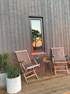 two chairs and a table on a deck with a window at Superfint boende med havsutsikt, Tofta Strand in Visby