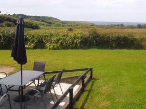 a table and chairs with an umbrella and a field at Rossnowlagh Creek Holiday House in Rossnowlagh