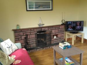 un soggiorno con camino e TV di Rossnowlagh Creek Holiday House a Rossnowlagh