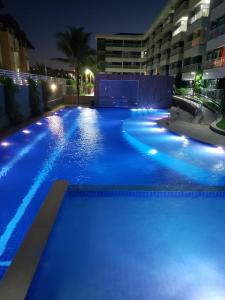 una piscina por la noche con luces azules en Apartamento com vista pro mar - Beach Way, en Aquiraz