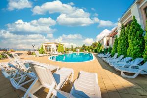 a group of lounge chairs next to a swimming pool at Sea View Panoramic Apartments, Fort Noks Crown Club in Sveti Vlas