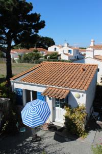 a blue and white umbrella in front of a house at Petit studio CYPRÈS du BOIS in Noirmoutier-en-l'lle