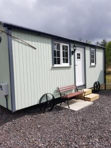 ein winziges Haus mit einer Bank und einem Picknicktisch in der Unterkunft Wee Highland Hideaway Hut in Dalmally