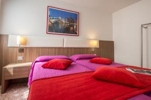 una camera da letto con un grande letto con cuscini rossi e viola di Hotel Il Moro di Venezia a Venezia